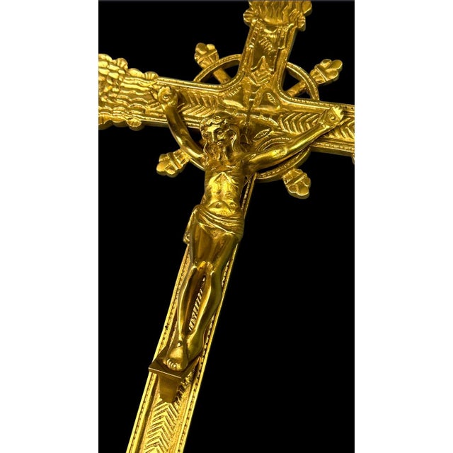 An ornate gilt bronze crucifix featuring detailed floral terminals and a central corpus figure. These altar crucifixes...