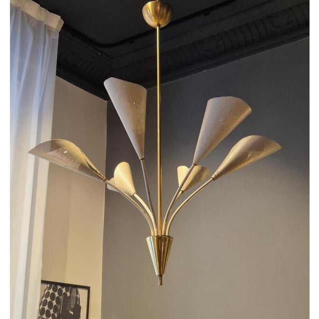 An elegant Mid-Century chandelier in brass and white perforated metal shades. In the manner of Mathieu Matégot, Bent...