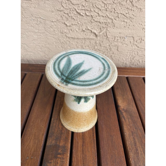 This object is a studio art pottery stand, commonly used as a candleholder or a cake stand. This specific piece features a...