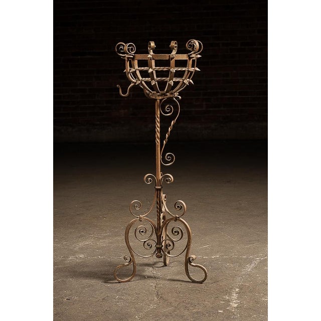 Hand-forged wrought iron jardinière stand featuring a basket-form top constructed from riveted strapwork, encircled by...