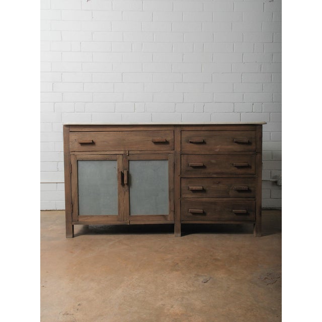 A character-rich wooden sideboard featuring a warm, weathered finish, a smooth marble top, and a balanced combination of...