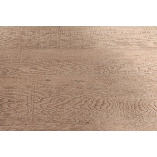 A stylish round dining table pairing a reclaimed pinewood top with an elegant sculptural pedestal stem base. The circular...