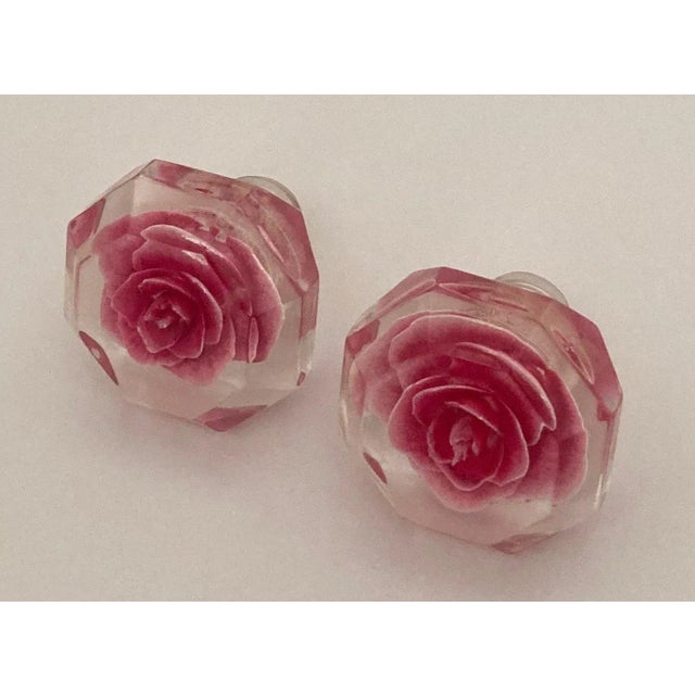Reverse carved magenta rose incased in clear lucite with set screws. The pair would make a nice showing on a powder room...