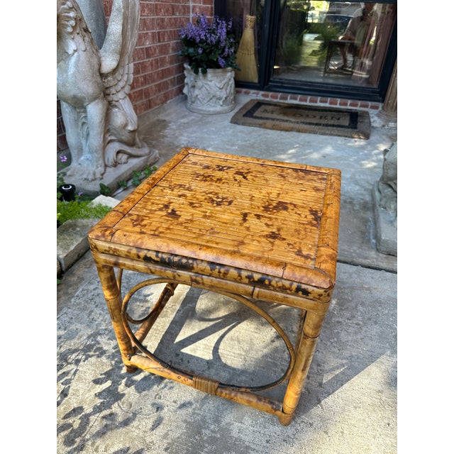 A striking vintage tortoise bamboo side table featuring a richly mottled frame and sculptural curved stretchers that...