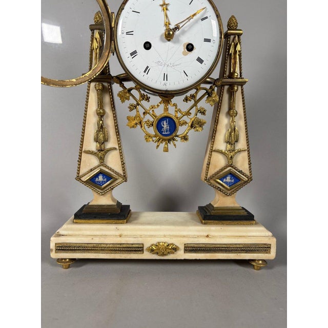 Louis XVI period portico clock. Portico clock with two white marble columns on a black marble base. Adorned with a gilt...