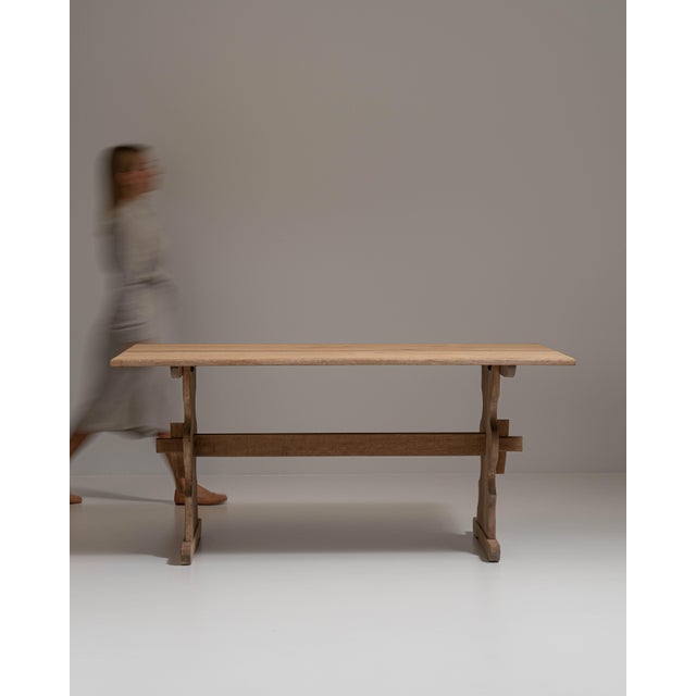 This 20th century oak trestle table from France is made in pale oak with a dark trestle base. The solid trestle base and...