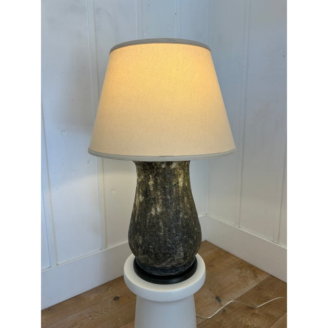 Heavy ceramic table lamp with a dark volcanic glaze finish and original linen shade. Measures 33 inches high overall....
