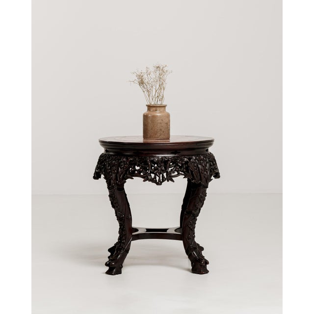 A decorative pedestal table featuring intricate carved detailing and a marble top. The craftsmanship reflects traditional...