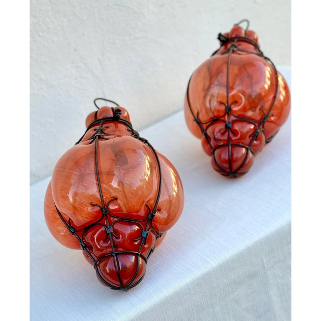 Gorgeous Mid-century Murano blown glass lanterns in swirls of coral and orange in their iron caged style framework. Each...