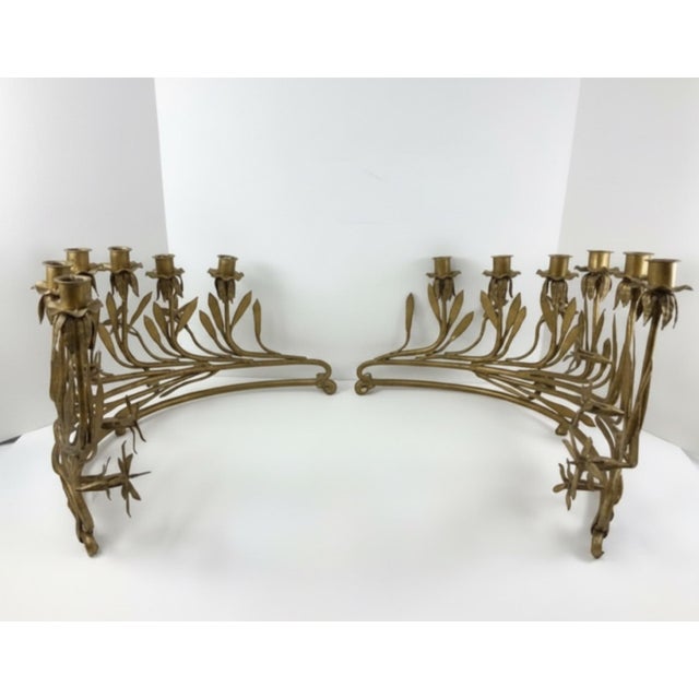 An unusually sculptural pair of gilt wrought-iron candelabra featuring an elaborate botanical design of sweeping stems,...