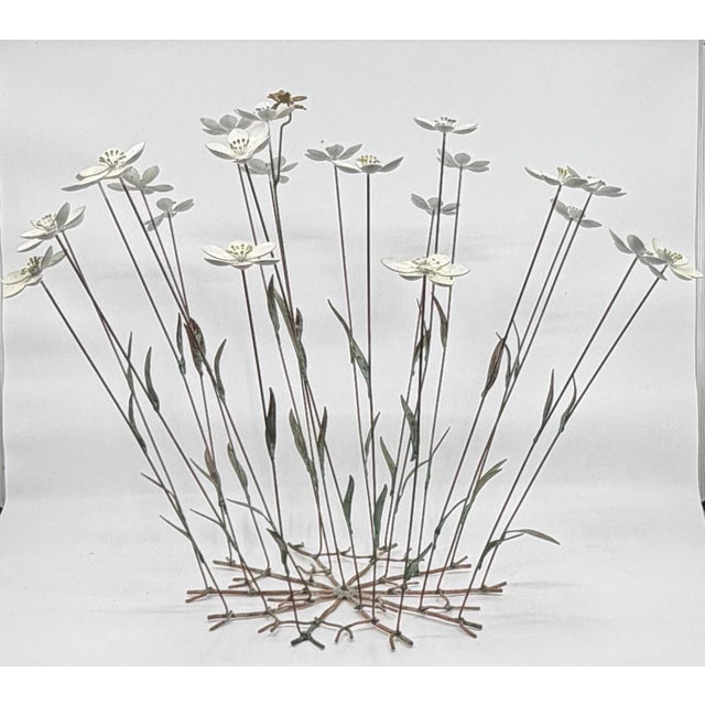This mid-century kinetic sculpture depicts a cluster of flowering stems with a single bee resting on one of the blossoms....