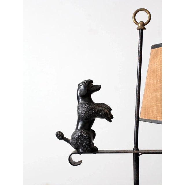 This is a vintage wrought iron table lamp. The scroll based figurative dog lamp features a decorative poodle perched on a...