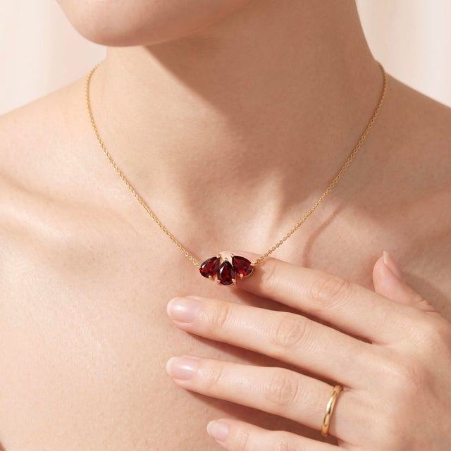 Elevate your everyday style with this elegant cluster pendant necklace, featuring three rich, deep-red gemstones arranged...