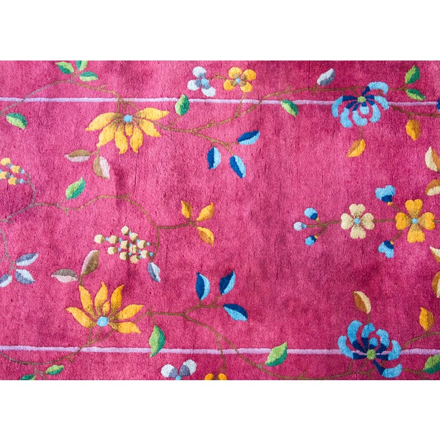 This vibrant 1930s Chinese Art Deco rug features a bold magenta field adorned with a delicate floral and vase motif. Hand-...
