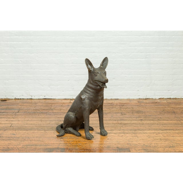 A contemporary bronze sculpture depicting a sitting German Shepherd with dark patina. Created with the traditional...