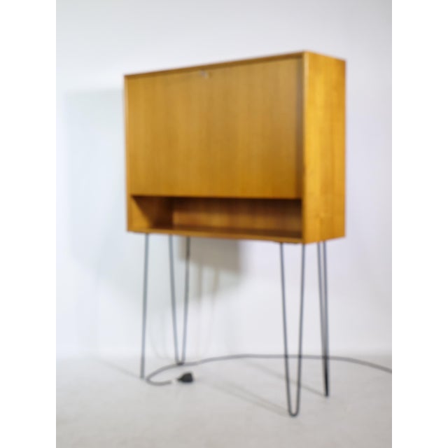Illuminated teakwood secretary on hairpin legs. Manufacturer: WK Möbel. Width: 100 cm Height: 146 cm Depth: 33 cm Shelf...
