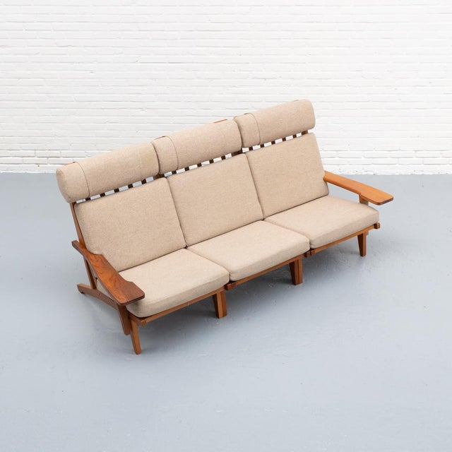 Danish three-seater sofa from the 1960s, designed by Hans J. Wegner for Getama. Solid oak frame with loose beige fabric...