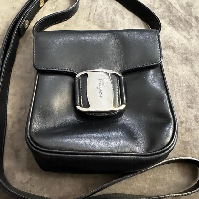 A charming and effortlessly chic black leather micro shoulder bag by Salvatore Ferragamo. a testament to enduring Italian...