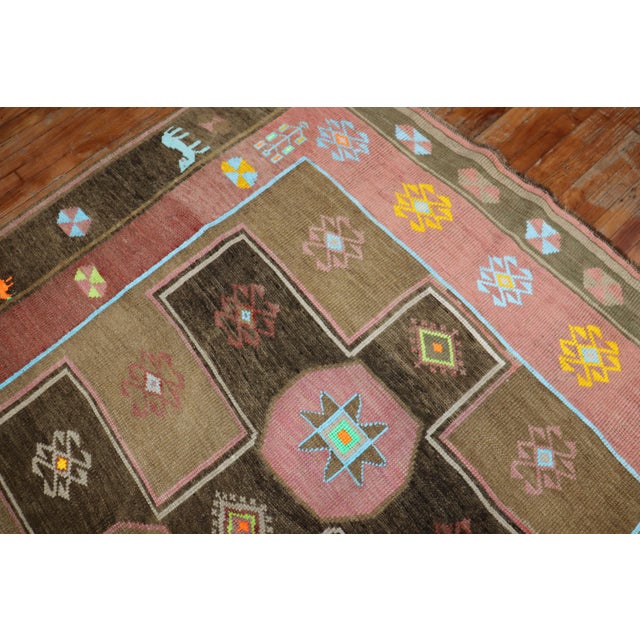 A whimsical mid-century colorful Turkish Kars rug. Field is brown, the border has 2 human figures and animals. Measures:...