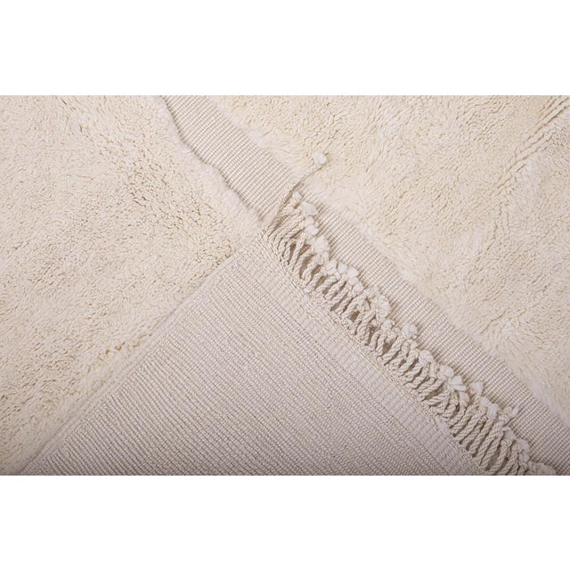 Artistic hand-knotted wool rug features a striking abstract block pattern in soft neutral tones. Its high-low pile texture...