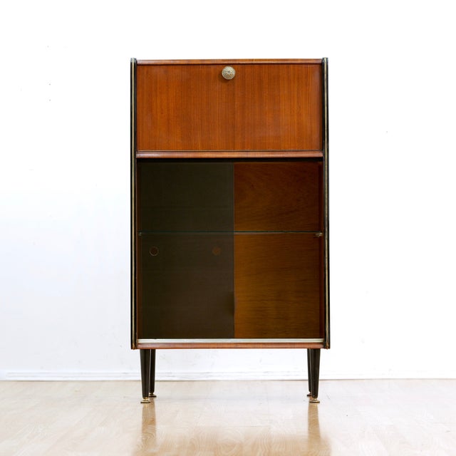 This fabulous mid century bar cabinet was made in England during the 1960s. Produced in Mahogany, the top cabinet doors...