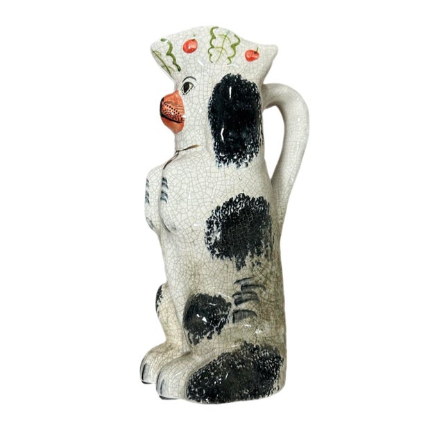 Staffordshire begging dog water pitcher. Colors are black, off white and various splashes of decorative color. Measures:...