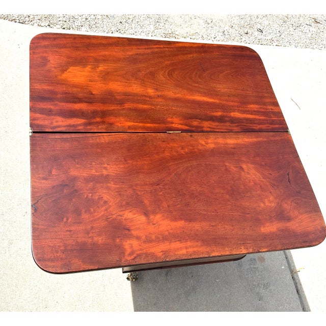 This is an antique, flame-mahogany, Regency-style, rotating, flip-top, game table, seated on top of a beautifully carved...