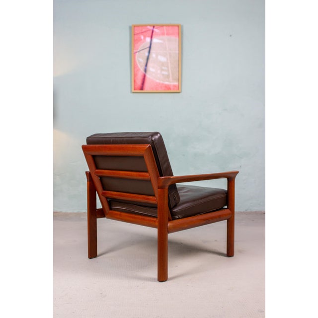 Two Danish teak armchairs made of solid wood with brown leather upholstery. Designed by Sven Ellekaer, manufactured by...