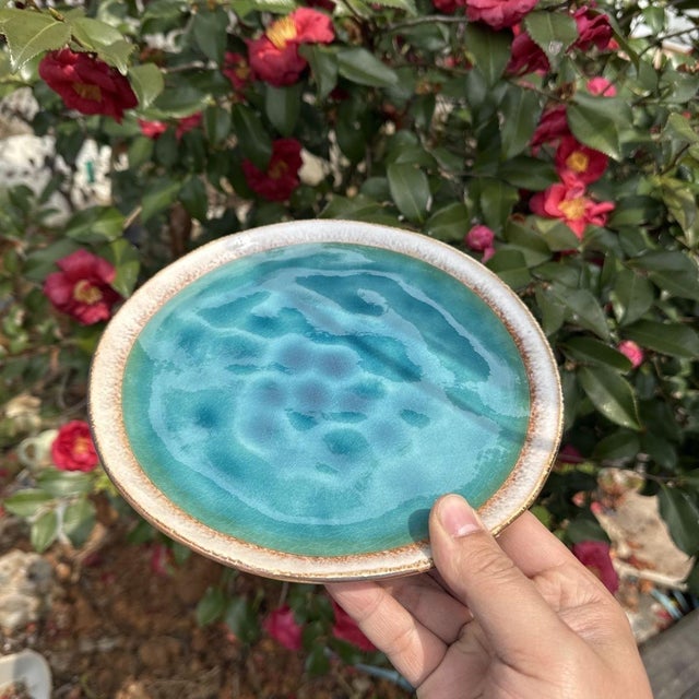 Made of ceramic, the kiln-transformation process creates a blue-green speckled texture, with some areas exhibiting an ice-...