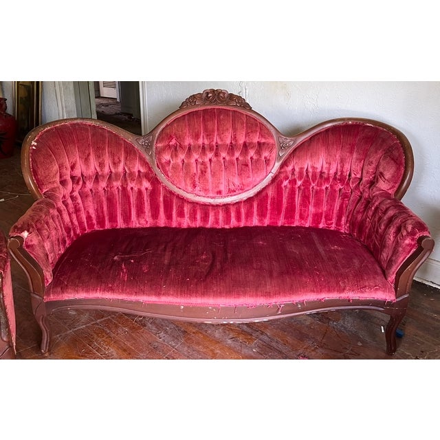 A matched Victorian style parlor set — a serpentine settee and a gentleman's armchair — both in beautifully carved dark...