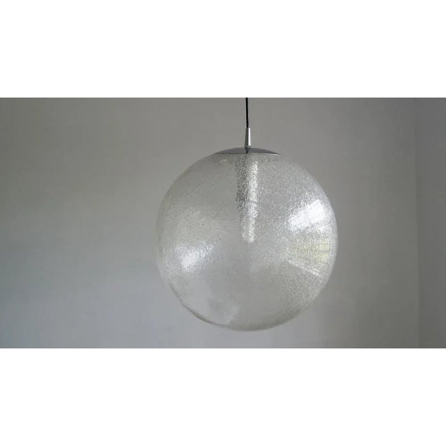 The large pendant lamp was manufactured by Peill & Putzler . Made from a hand-blown clear glass sphere that completes its...
