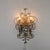 The lamp features flowing tendrils and ornamental curls in gilded metal. A silvered crystal glass element sits at its...