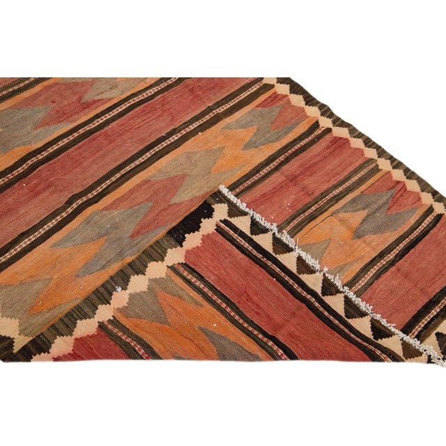 Beautiful vintage Turkish Kilim hand-knotted wool rug with an orange field. This piece has a beige frame and multicolor...