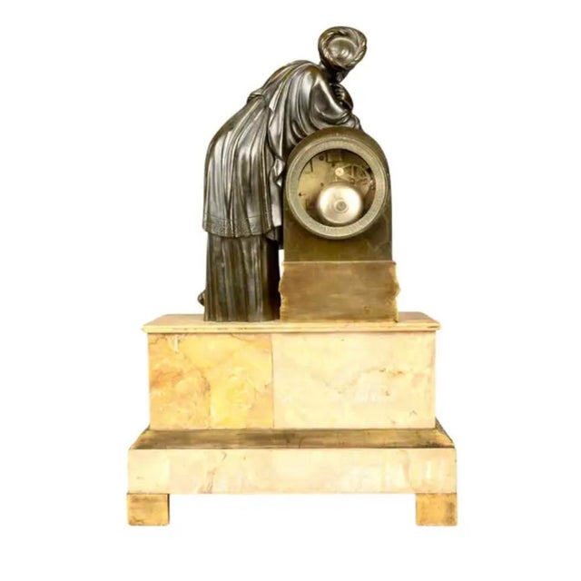 A luxurious and elegant Neoclassical patinated and gilt bronze Minerva standing leaning on the clock, classically robed...