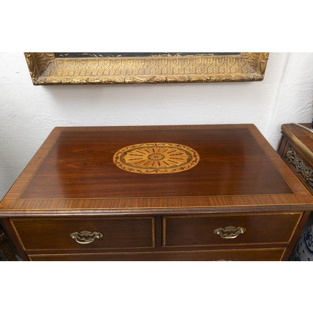 An elegant Federal-style mahogany chest of drawers, featuring a beautifully figured top centered by an oval satinwood and...
