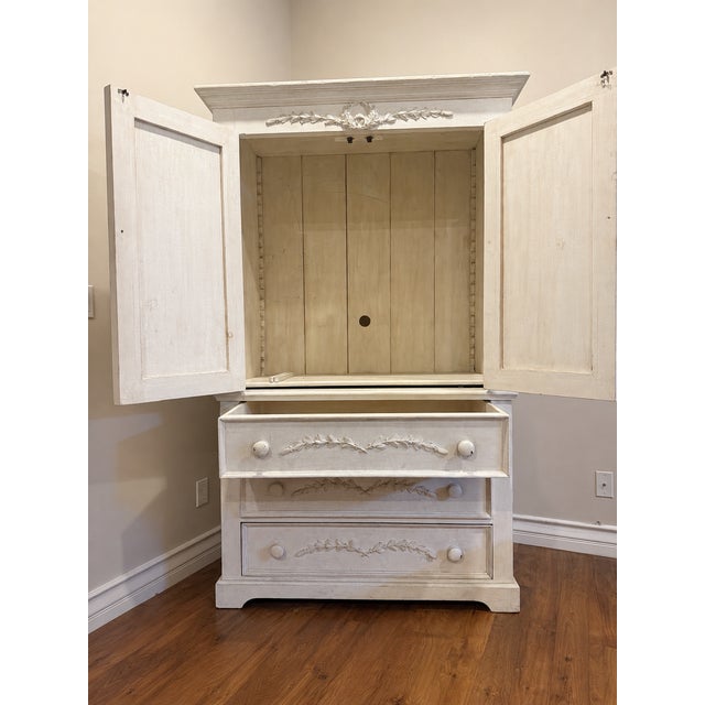 A beautifully crafted vintage armoire in an original distressed cream finish with delicate crackle patina and hand-carved...