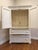 A beautifully crafted vintage armoire in an original distressed cream finish with delicate crackle patina and hand-carved...