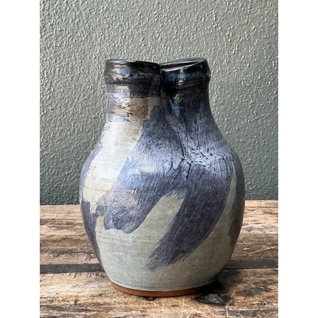 This vintage ceramic vase brings mid-century modern sensibility to life through its distinctive double-neck silhouette,...