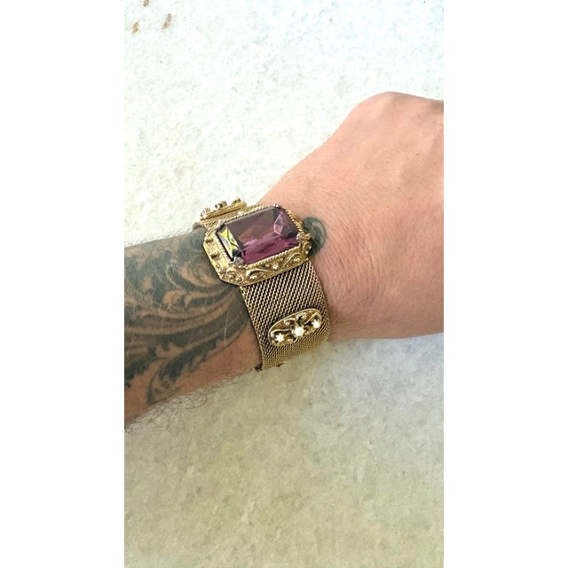 Gold-tone woven mesh slide bracelet featuring an ornate rectangular center setting with a deep purple