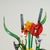 Lofty dramatic hand blown glass sculpture having a floral bouquet of exotic flowers and leaves presented in an alluring...