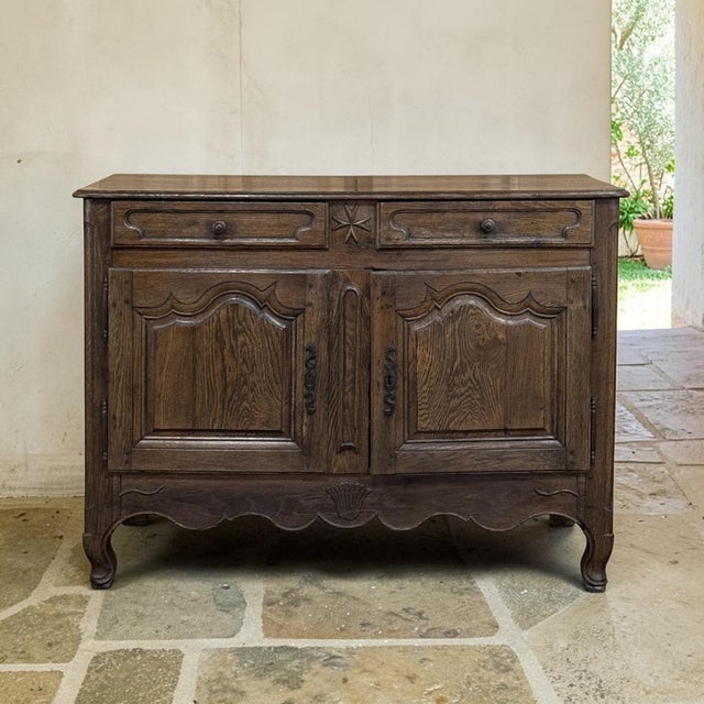 An 18th century Country French Louis XV buffet in solid oak, glowing with a deep, rich patina earned over centuries of...