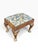 This antique footstool features a Queen Anne style design with cabriole legs. It is upholstered in fabric attributed to...