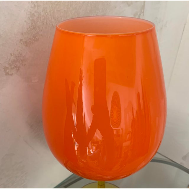 This grand bright piece was handblown in the most vibrant orange and finished with an amber stem. It’s interior is cased...