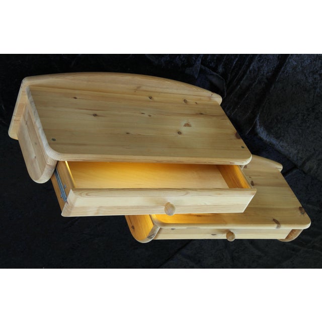 A set of two floating bedside shelves in solid pine wood. Their thick, rounded design gives them a brutalist yet...
