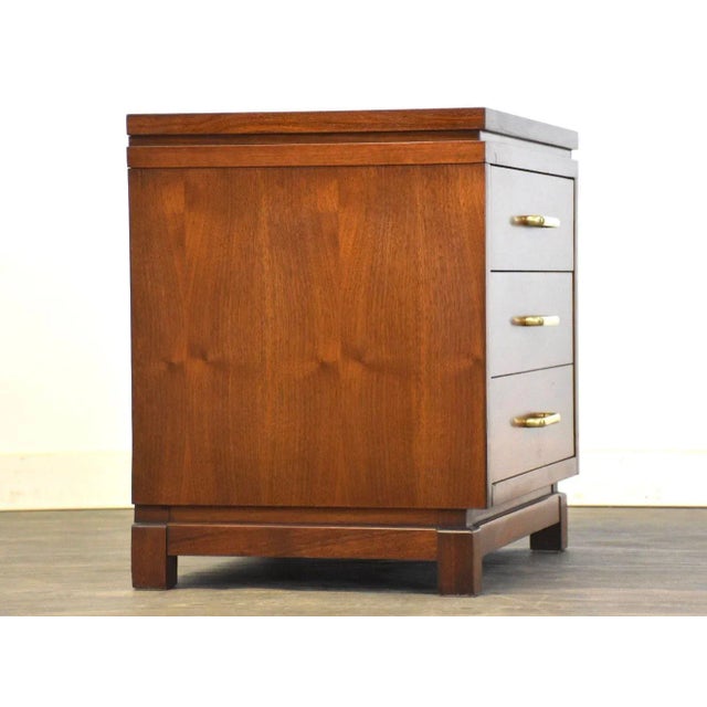 A mid century modern walnut two drawer nightstand with brass drawer pulls made by Ramseur Furniture. 22.25” wide. 17”...