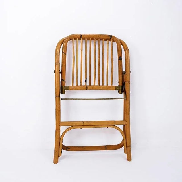 Handmade folding chair in perfectly proportioned curved bamboo. Measures : 53cmx44cm H:72cm SH:46cm Materials: Bamboo - Brass