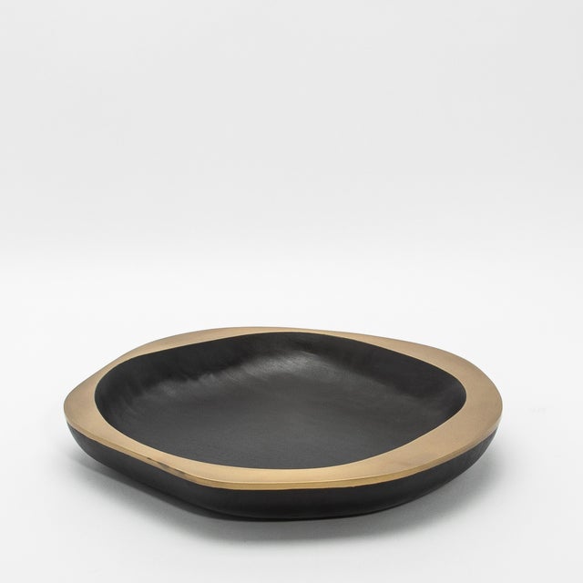 The Lily Bowl in black oak with bronze patina brass details by R&Y Augousti is a stunning embodiment of organic elegance...