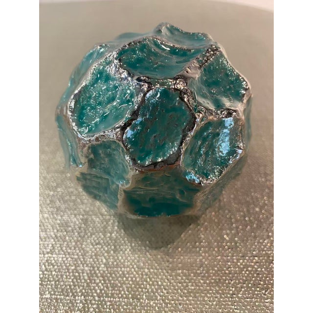 This visually captivating decorative ball possesses a stunning green hue accented by organically shaped ridges in a Nickel...