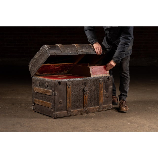 Domed-top immigrant steamer chest constructed in wood with a fully clad embossed metal exterior, reinforced by iron...