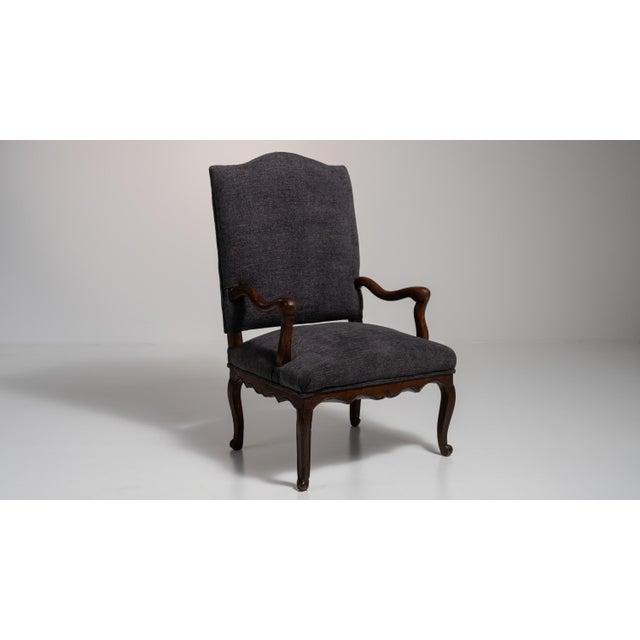 A black wood, Louis XV-style armchair, dating to the 19th century and made in France. The wood frame is finished in...